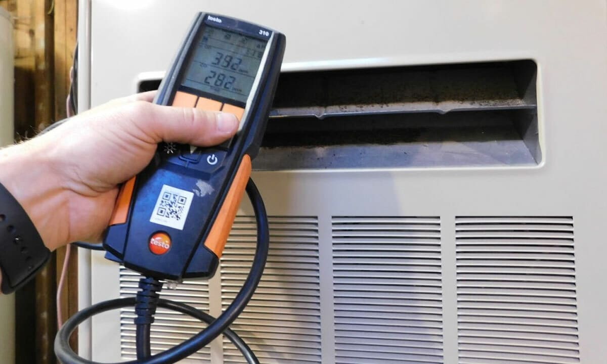 An HVAC technician inspecting a furnace with digital gauges