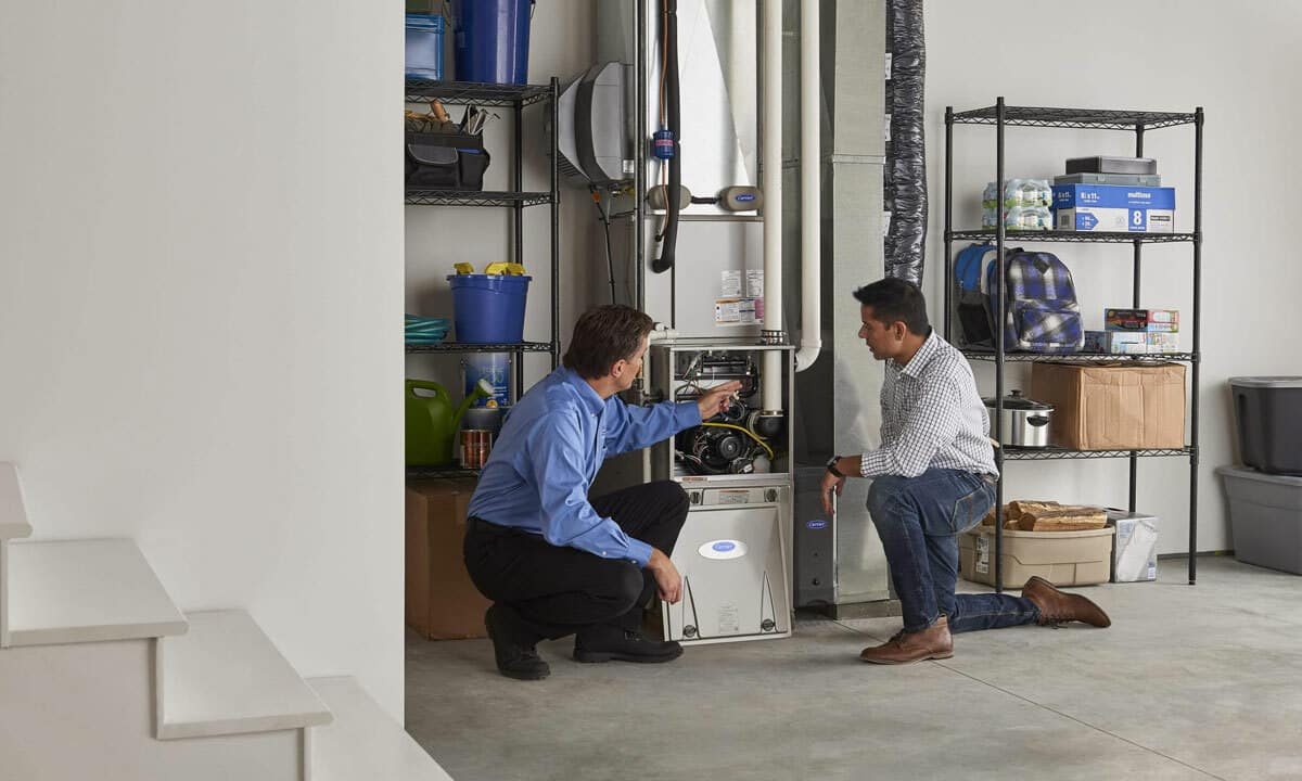 A technician and homeowner inspect a furnace together