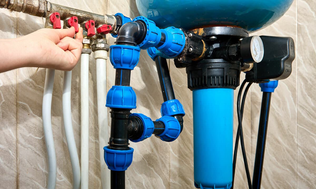 Photo of a home water filtration system with someone adjusting the dials