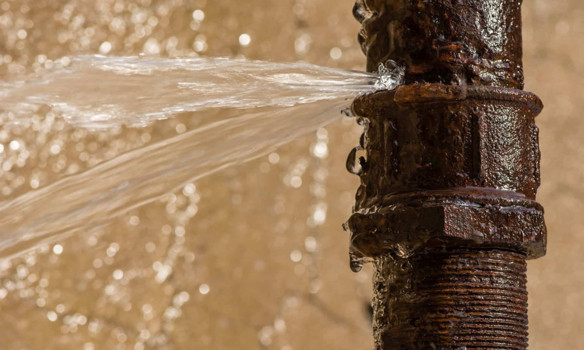 A detailed upclose photo of a pipe bursting with water