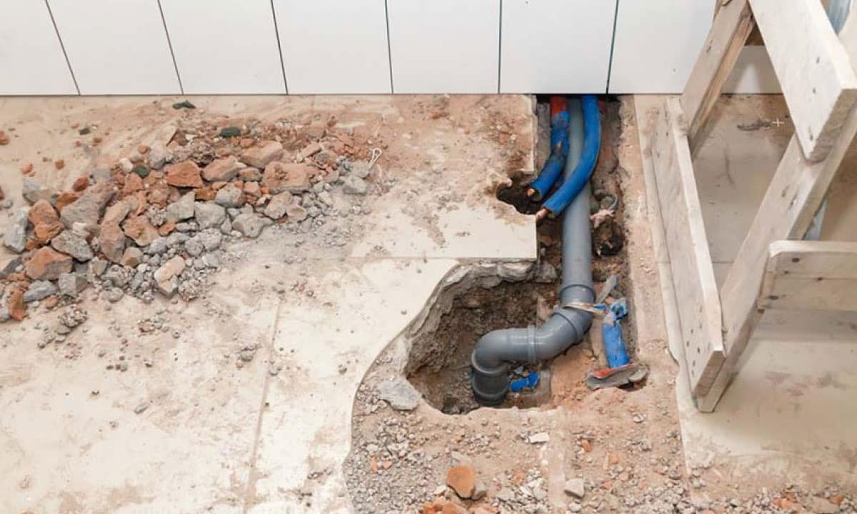 A partially exposed drain pipe under a floor