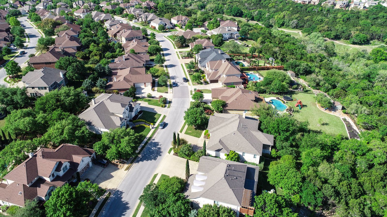 An overhead view of homes on a tree-lined street.