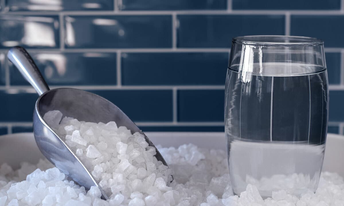 A glass of water sitting on a pile of salt used in water softeners